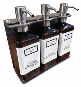 photo of Beekman three-chamber wall-mounted hotel dispenser set, with individual units for Shower Gel, Shampoo, and Conditioner.